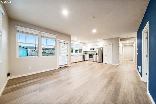 unfurnished living room featuring light hardwood / wood-style floors, a textured ceiling, and a wealth of natural light