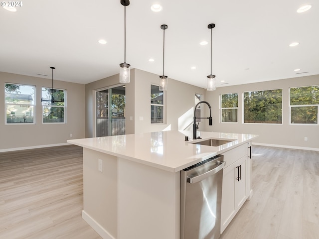 kitchen featuring dishwasher, hanging light fixtures, a kitchen island with sink, and sink