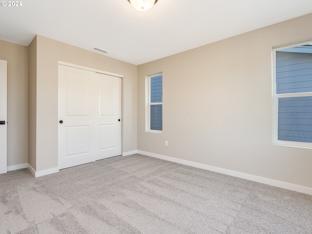 unfurnished bedroom featuring light colored carpet and a closet