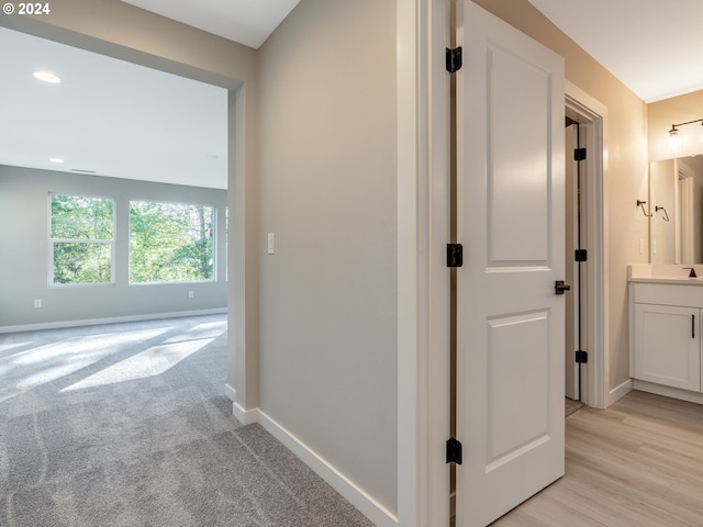 corridor with sink and light hardwood / wood-style flooring