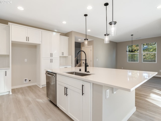 kitchen featuring pendant lighting, dishwasher, a center island with sink, sink, and white cabinetry