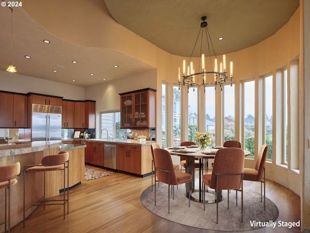 dining space with a mountain view, a notable chandelier, light hardwood / wood-style floors, and a healthy amount of sunlight