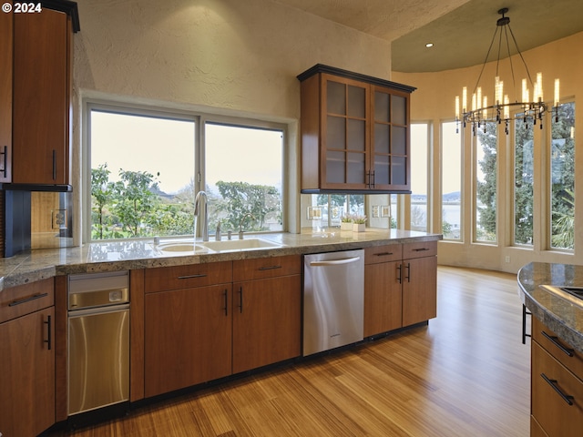 kitchen with an inviting chandelier, light wood-type flooring, dishwasher, and a healthy amount of sunlight