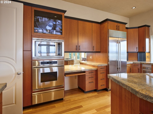 kitchen with decorative backsplash, light hardwood / wood-style floors, and built in appliances