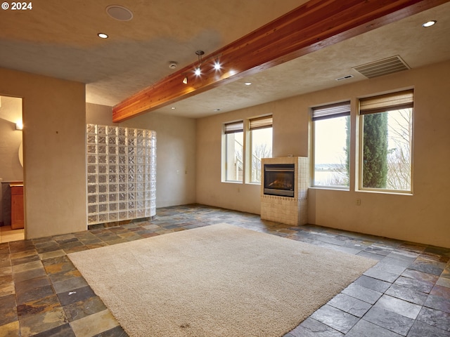 unfurnished living room featuring beam ceiling and a fireplace