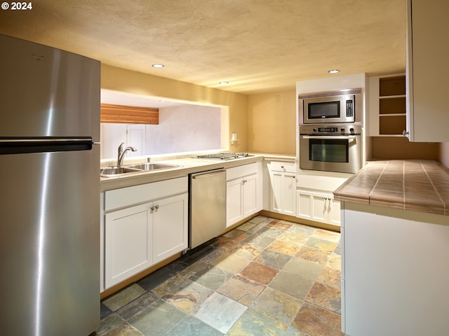 kitchen featuring white cabinetry, sink, stainless steel appliances, and tile countertops