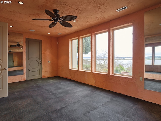 spare room with a water view, ceiling fan, and a healthy amount of sunlight