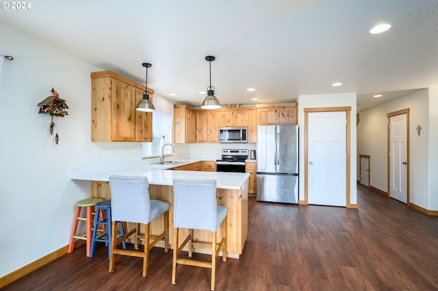 kitchen with kitchen peninsula, stainless steel appliances, sink, dark hardwood / wood-style floors, and hanging light fixtures