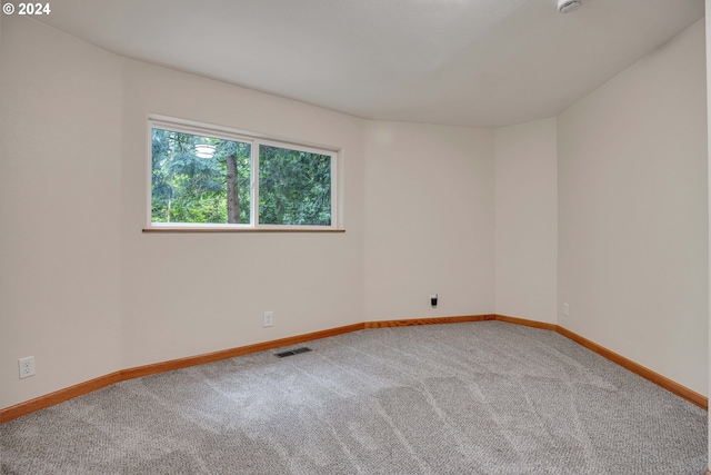 carpeted spare room with lofted ceiling with skylight