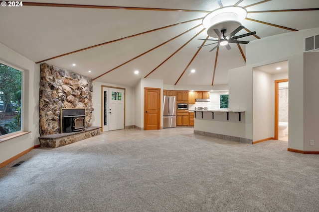 unfurnished living room featuring ceiling fan, light colored carpet, a fireplace, and lofted ceiling