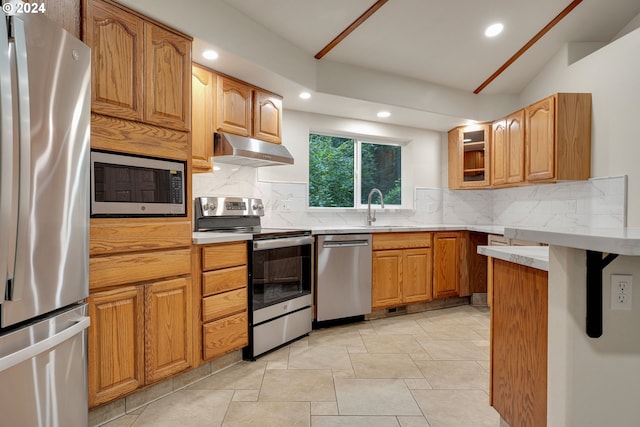 kitchen with decorative backsplash, sink, stainless steel appliances, and light stone counters