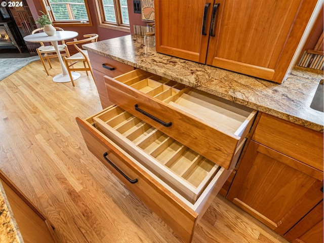 interior details featuring light stone countertops, light wood-type flooring, and a wood stove