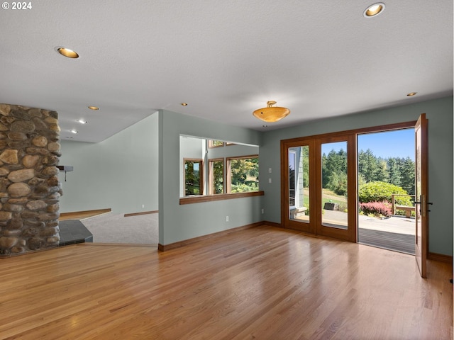 interior space with a textured ceiling, light hardwood / wood-style flooring, and french doors