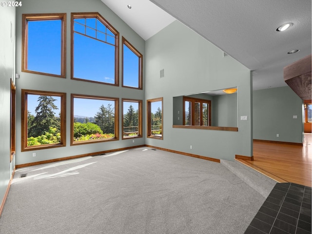 unfurnished living room with carpet flooring and high vaulted ceiling