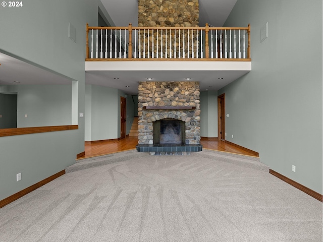 unfurnished living room featuring carpet flooring, a high ceiling, and a stone fireplace