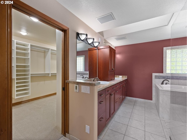 bathroom with tile patterned flooring, vanity, a healthy amount of sunlight, and tiled tub