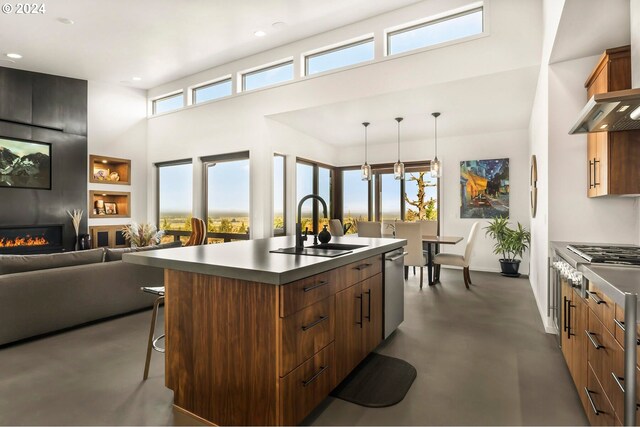 kitchen with an island with sink, sink, a large fireplace, a breakfast bar area, and pendant lighting