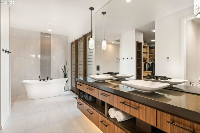 bathroom with tile walls, vanity, a bath, and tile patterned floors