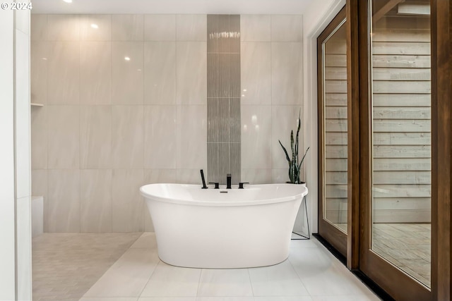 bathroom with tile walls, a tub, and tile patterned floors