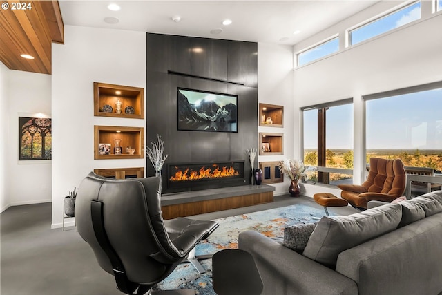 home theater featuring a fireplace, a towering ceiling, and built in shelves