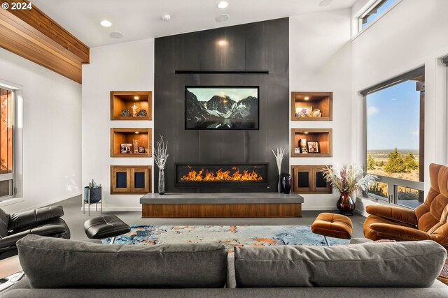 living room with high vaulted ceiling, built in features, and a large fireplace