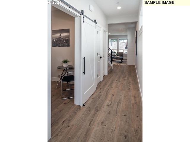 hallway with a barn door and hardwood / wood-style flooring