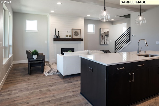 kitchen with a large fireplace, a healthy amount of sunlight, sink, and a kitchen island with sink