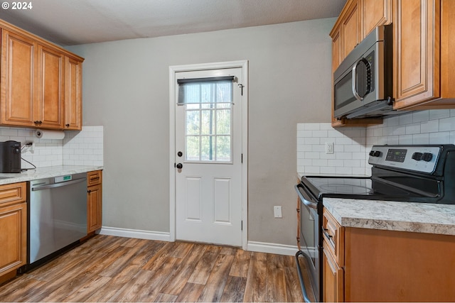 kitchen featuring a textured ceiling, appliances with stainless steel finishes, dark hardwood / wood-style flooring, and decorative backsplash