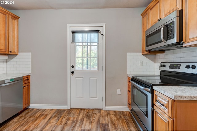 kitchen featuring a textured ceiling, appliances with stainless steel finishes, backsplash, and hardwood / wood-style floors