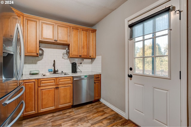 kitchen with wood-type flooring, a textured ceiling, tasteful backsplash, sink, and stainless steel appliances