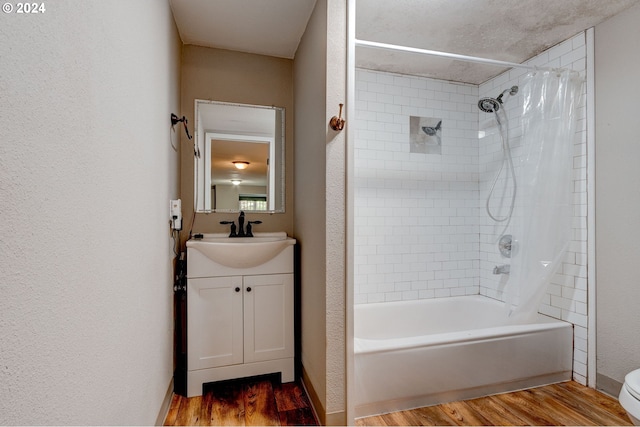 full bathroom with vanity, hardwood / wood-style flooring, tiled shower / bath combo, and toilet