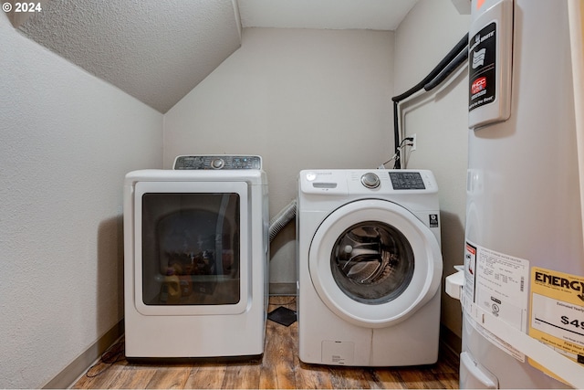 washroom with water heater, washer and dryer, a textured ceiling, and hardwood / wood-style flooring