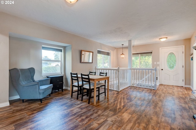 dining area with an inviting chandelier, a wealth of natural light, a textured ceiling, and dark hardwood / wood-style flooring