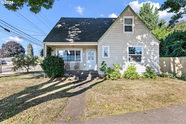 view of front of property with a shingled roof, fence, and a front yard