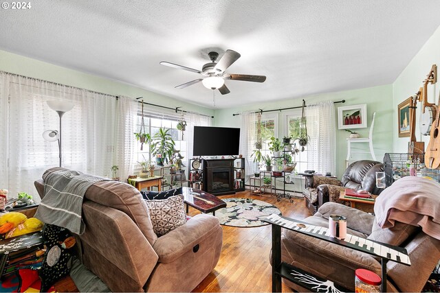 living room with ceiling fan, light hardwood / wood-style floors, and a textured ceiling