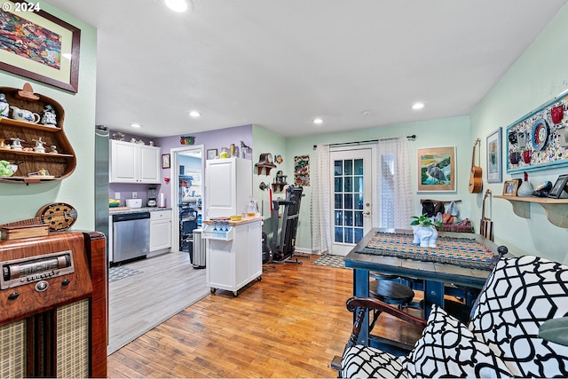 kitchen featuring stainless steel dishwasher, light wood-type flooring, and white cabinetry