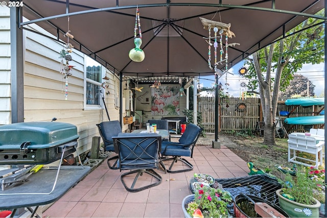 view of patio featuring outdoor dining area, fence, grilling area, and a gazebo