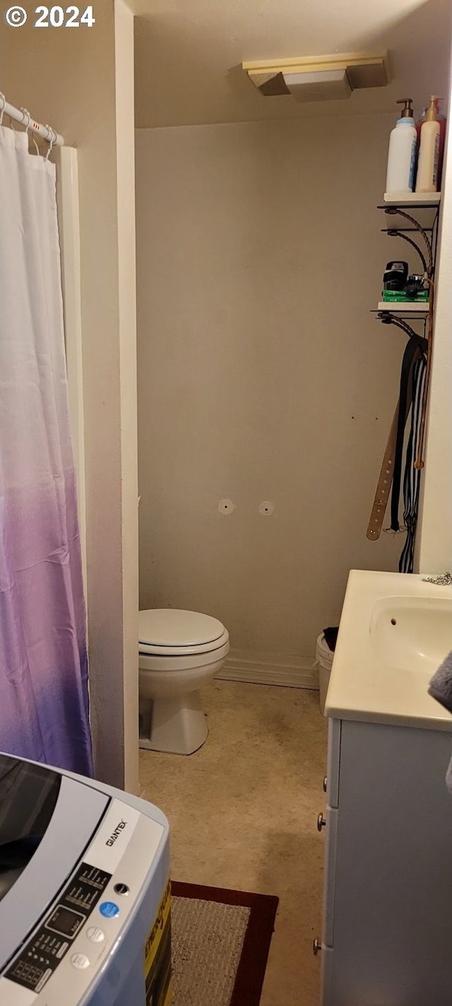 bathroom featuring vanity, toilet, curtained shower, and washer / clothes dryer