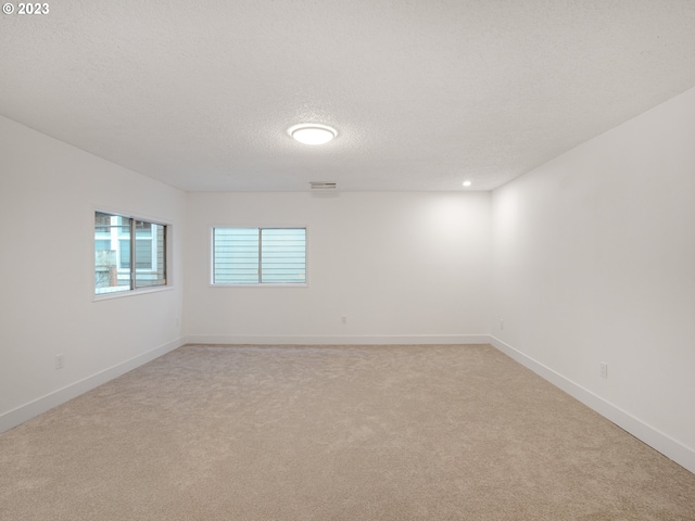 carpeted empty room featuring a textured ceiling