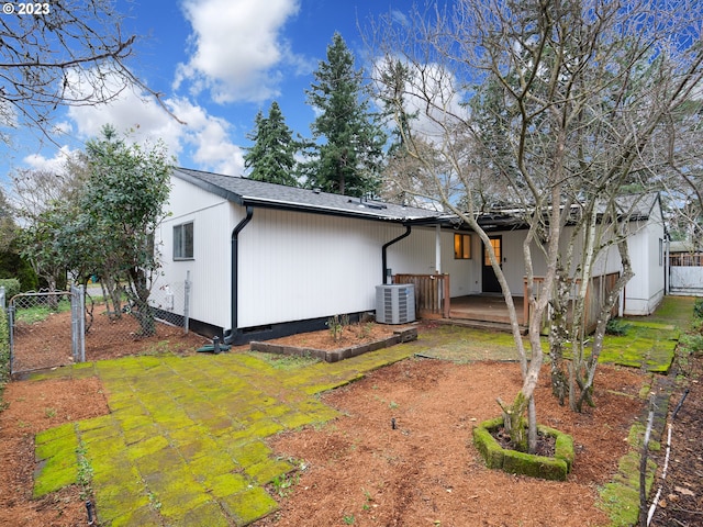 rear view of house featuring cooling unit, a lawn, and a patio