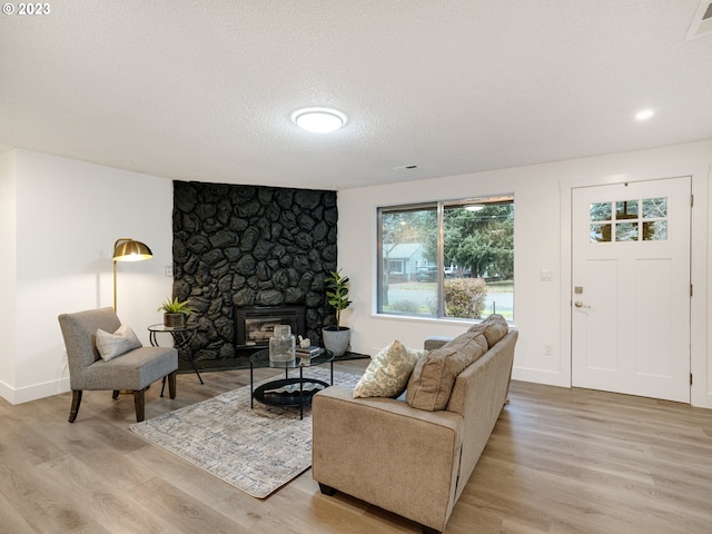 living room featuring a fireplace, a textured ceiling, and light hardwood / wood-style floors