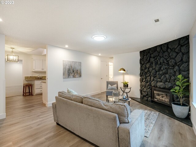 living room featuring a fireplace, light hardwood / wood-style flooring, and a textured ceiling