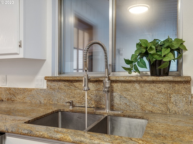 room details with decorative backsplash, stone counters, sink, and white cabinetry