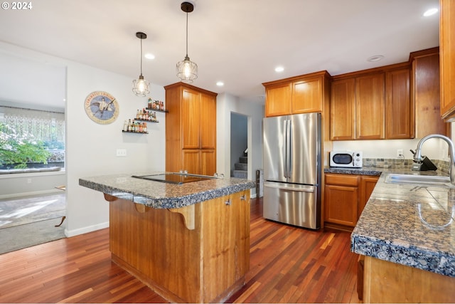 kitchen featuring dark wood-type flooring, sink, decorative light fixtures, and stainless steel refrigerator