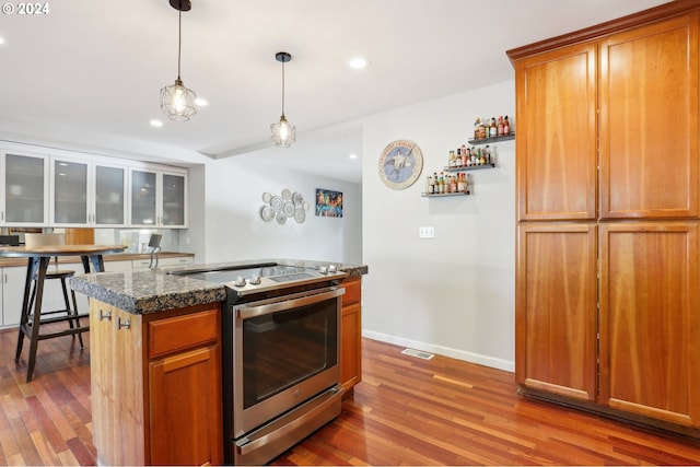 kitchen featuring pendant lighting, hardwood / wood-style flooring, dark stone countertops, and stainless steel range with electric cooktop