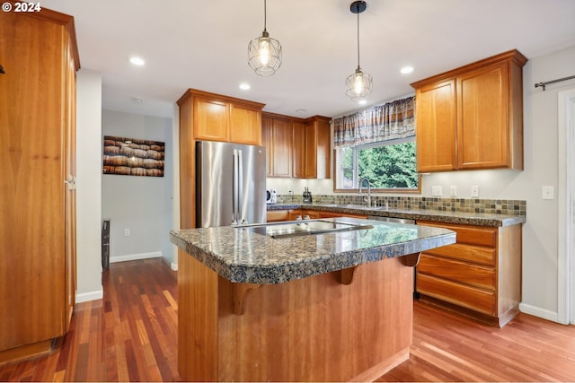 kitchen featuring stainless steel fridge, dark hardwood / wood-style floors, pendant lighting, and a breakfast bar area