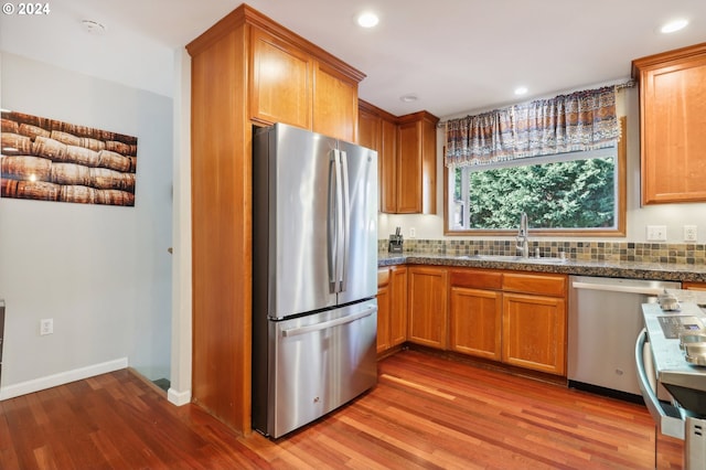 kitchen with decorative backsplash, stainless steel appliances, light hardwood / wood-style floors, and sink