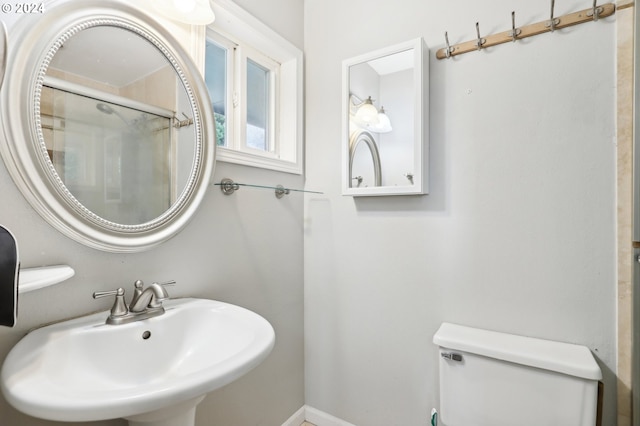 bathroom featuring sink, an enclosed shower, and toilet