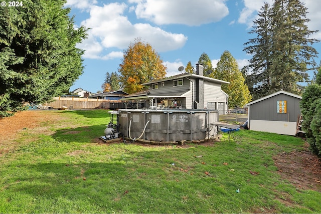 rear view of house featuring a fenced in pool, a lawn, and an outbuilding