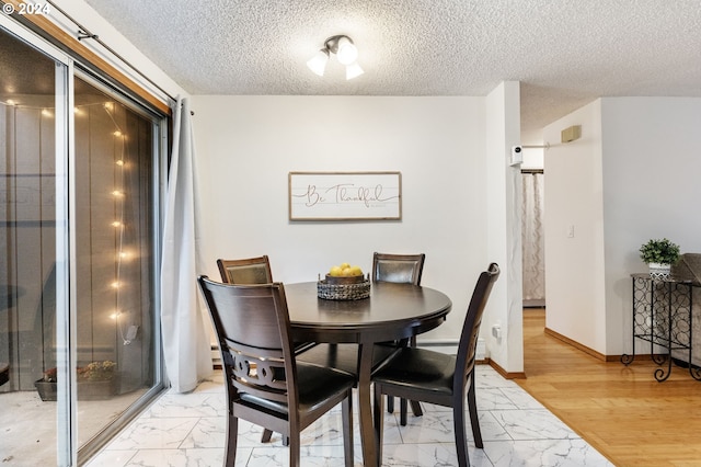 dining area with light hardwood / wood-style flooring and a textured ceiling